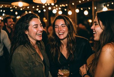 Friends laughing together at a lively cafe party under string lights