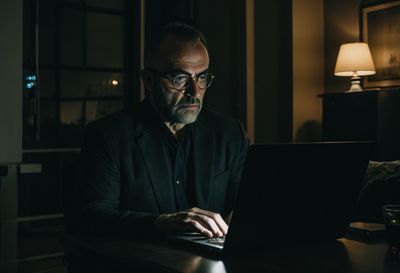 A founder at night looking skeptically at a glowing laptop screen