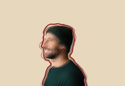 A smiling man in a beanie seen from the side, overlaid with shifted, faded copies of himself and outlined by a hand-drawn red line